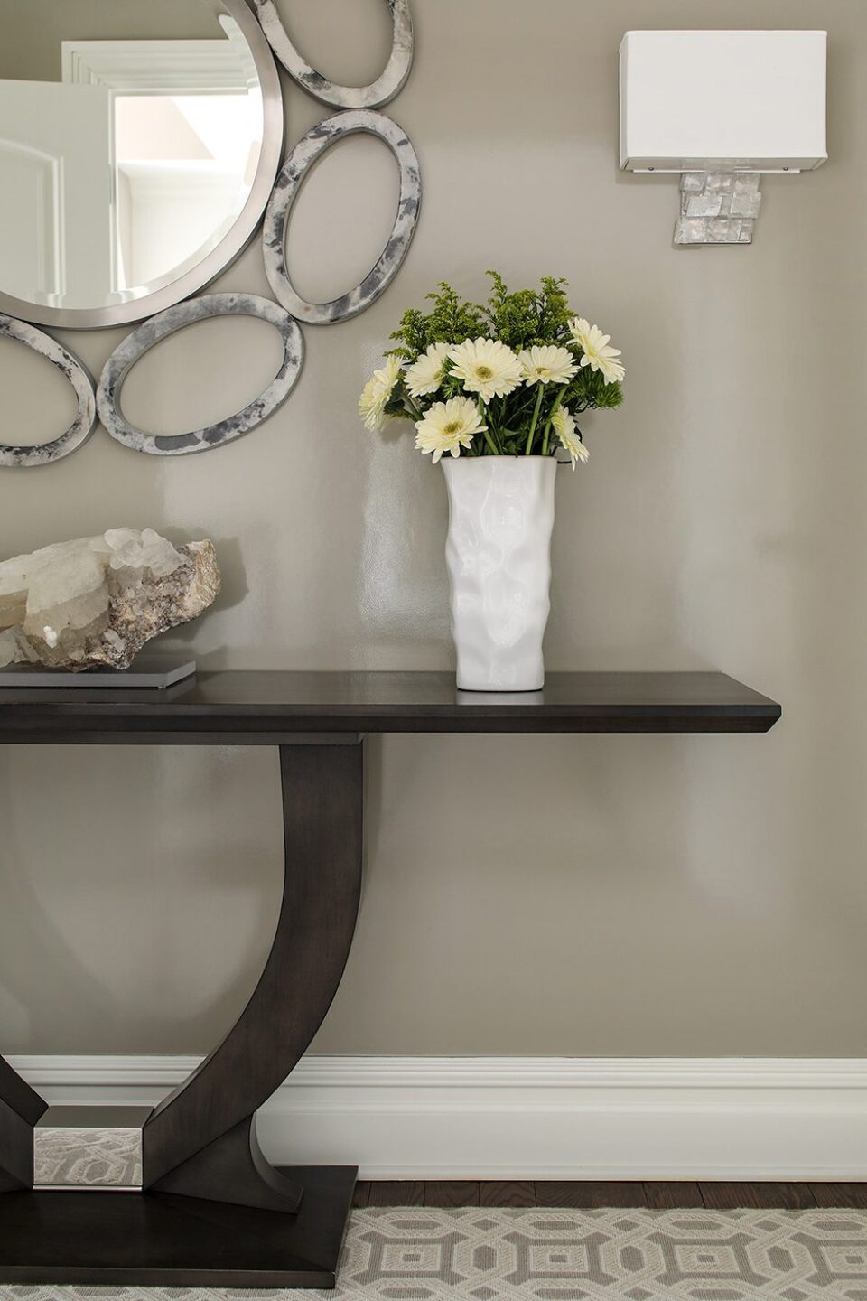White Vase With Flowers On End Of Wooden Table